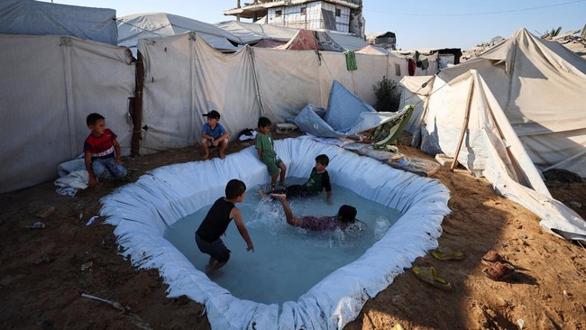 Displaced Palestinian children play in a makeshift pool to cool down on a hot summer day at a tent camp where they shelter, in Gaza City, July 17, 2026. REUTERS/Dawoud Abu Alkas