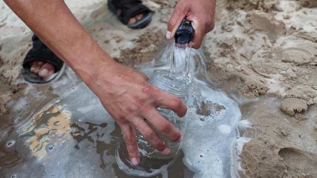 A Palestinian man fills a jar with water, in Gaza City, July 14, 2026. REUTERS/Dawoud Abu Alkas