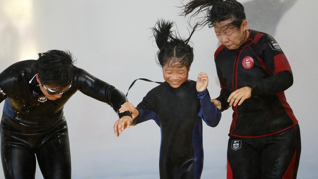 Participants walk through simulated typhoon-force wind and rain during a typhoon survival training session at the Lvxing Disaster Simulation Training Center in Hangzhou, Zhejiang province, China July 15, 2026. REUTERS/Go Nakamura     TPX IMAGES OF TH