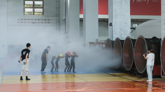 Participants walk through simulated typhoon-force wind and rain during a typhoon survival training session at the Lvxing Disaster Simulation Training Center in Hangzhou, Zhejiang province, China July 15, 2026. REUTERS/Go Nakamura