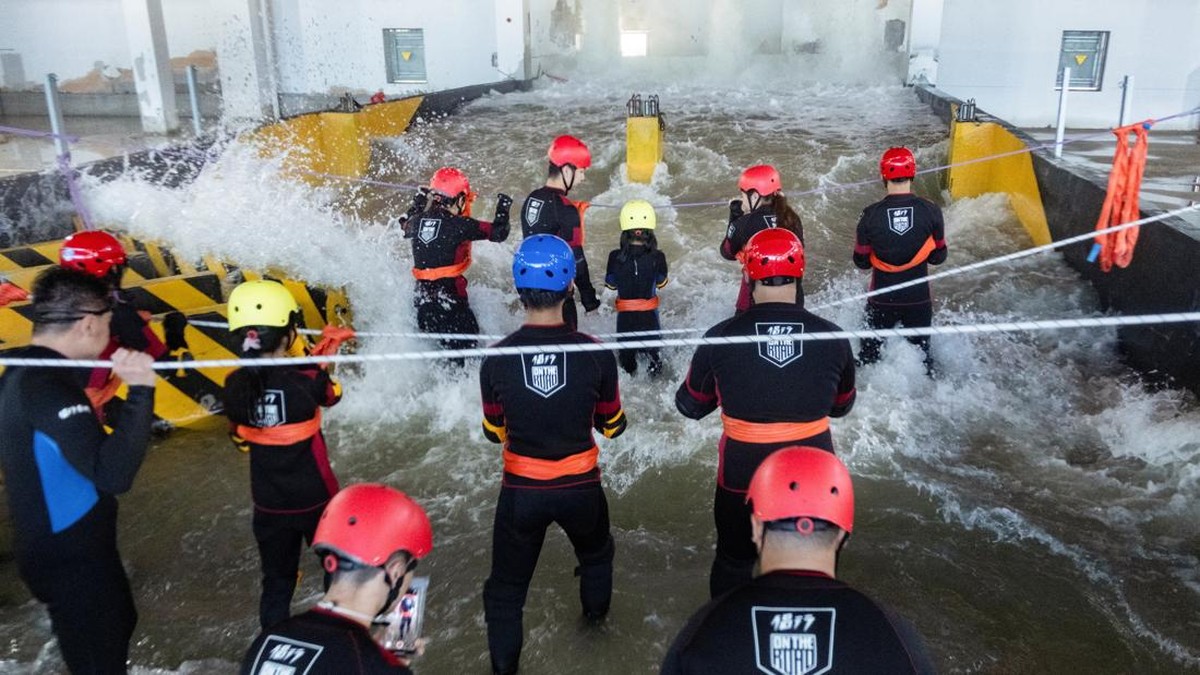 Participants brace for surging water in a flash flood simulator during a typhoon survival training session at the Lvxing Disaster Simulation Training Center in Hangzhou, Zhejiang province, China July 15, 2026. REUTERS/Go Nakamura
