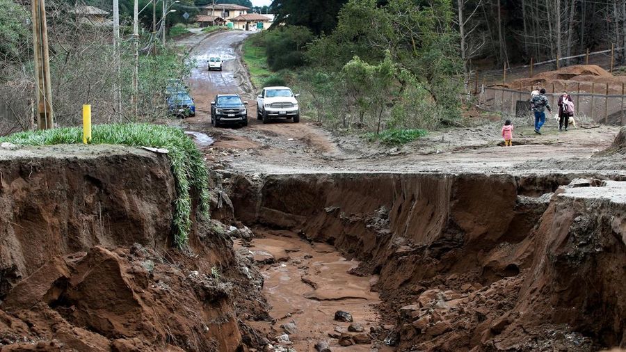 Pemandangan tanah longsor besar-besaran di sebuah jalan di lingkungan pinggiran kota setelah hujan lebat akibat front cuaca nan menyebabkan banjir dan mendorong pihak berkuasa Chili untuk menyatakan keadaan darurat preventif pada awal pekan ini, di