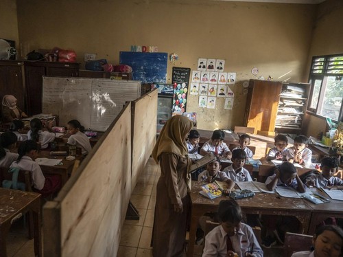 Sejumlah siswa kelas 3 dan 4 mengikuti kegiatan belajar mengajar di ruang kelas yang disekat akibat bangunan kelas ambruk di SD Negeri Tanggirejo, Tegowanu, Grobogan, Jawa Tengah, Selasa (21/7/2026).Menurut pihak sekolah menyebutkan bahwa atap bangun