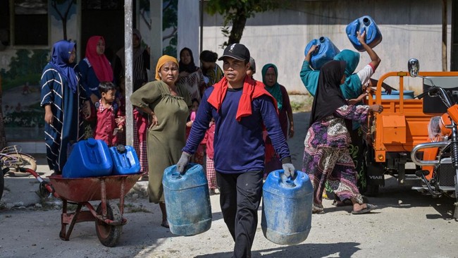 Villagers carry jerrycans to collect clean water distributed by the Indonesian Red Cross (PMI) in Batangan village, Bangkalan Regency, East Java Province on July 21, 2026, as residents struggled to access groundwater in their homes due to a prolonged