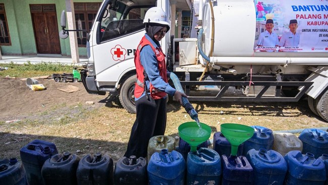An Indonesian Red Cross (PMI) volunteer fills residents jerrycans with clean water in Batangan village, Bangkalan Regency, East Java Province on July 21, 2026, as residents struggled to access groundwater in their homes due to a prolonged dry season