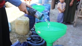 Relawan Palang Merah Indonesia (PMI) Kabupaten Bangkalan mengisi air bersih ke dalam jeriken milik warga di Dusun Batangan Tengah, Desa Batangan, Kecamatan Tanah Merah, Kabupaten Bangkalan, Jawa Timur, Selasa (21/7/2026). Dalam dua hari terakhir PMI