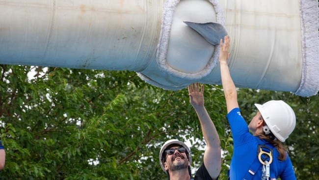 Members of a relocation team touch the flippers of a beluga whale, one of the first batch of six to be transported to aquariums in the U.S., being hoisted in a sling at the closed marine park Marineland Canada in Niagara Falls, Ontario, Canada July 2