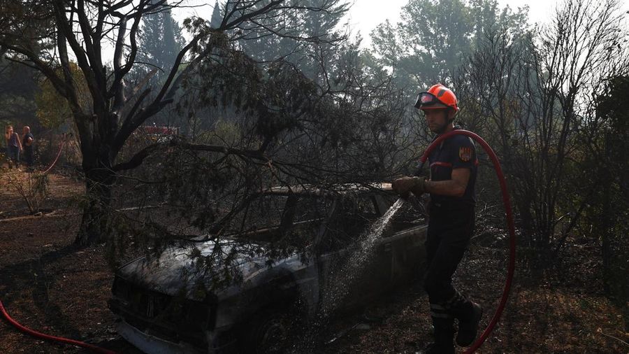 Petugas pemadam kebakaran Prancis menyemprotkan air di dekat mobil nan terbakar selama operasi pembersihan di dekat sebuah rumah nan terbakar di wilayah nan terkena akibat kebakaran rimba di Cotignac, di departemen Var, saat kondisi kekeringan memburuk setelah gelombang panas dan kekurangan air di sebagian besar Prancis, 22 Juli 2026.