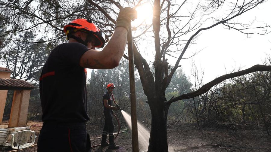 Petugas pemadam kebakaran Prancis menyemprotkan air selama operasi pembersihan di dekat sebuah rumah nan terbakar di wilayah nan terkena akibat kebakaran rimba di Cotignac, di departemen Var, saat kondisi kekeringan memburuk setelah gelombang panas dan kekurangan air di sebagian besar Prancis, 22 Juli 2026.