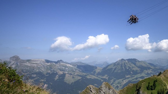 This photograph shows tourists enjoying the new BalancAIR, a giant swing at the top of the Grand Chamossaire peak, above Villars-sur-Ollon, western Switzerland, on July 20, 2026. Inaugurated at the beginning of the month, the Grand Chamossaire swing