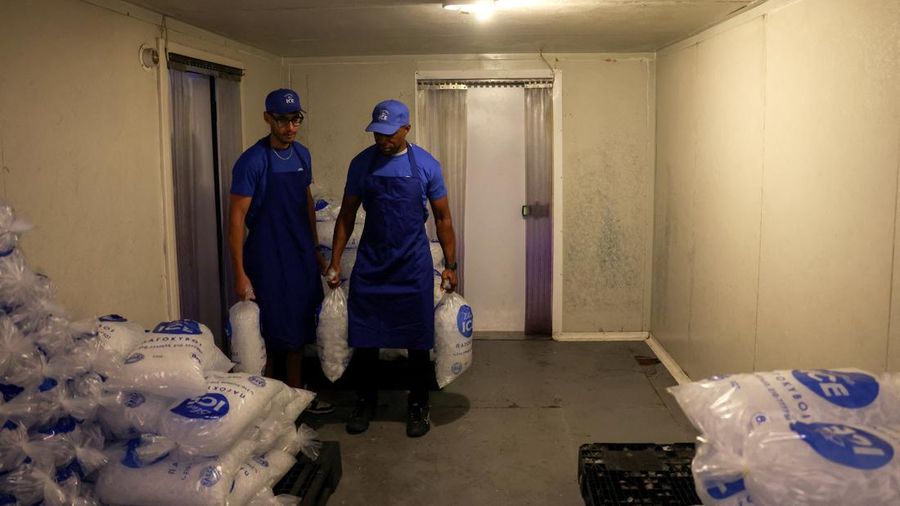 Karyawan Blue Ice, Aziz Lasnami dan Evans Osagie, membawa kantong-kantong es batu di akomodasi perusahaan selama gelombang panas di Athena, Yunani, 22 Juli 2026.