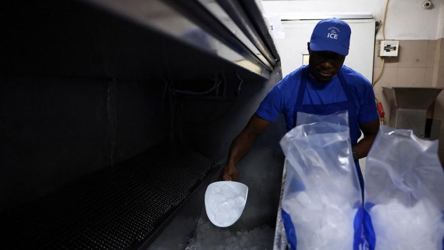 Karyawan Blue Ice, Evans Osagie, memasukkan es batu ke dalam kantong saat gelombang panas di Athena, Yunani, 22 Juli 2026. (REUTERS/Louiza Vradi)