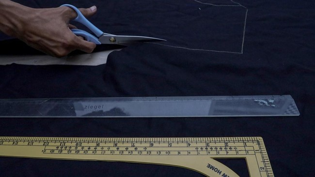 Pengrajin Bunay Ilhamulla memotong pola kain pelapis yang akan dipadukan dengan limbah jeans untuk pembuatan produk fesyen di rumah produksi Bumoe, Banda Aceh, Aceh.