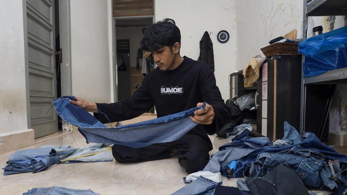 Pengrajin Bunay Ilhamullah memilah limbah kain jeans untuk diolah menjadi berbagai produk di rumah produksi Bumoe, Banda Aceh, Aceh.