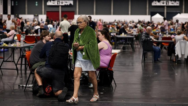 FILE PHOTO: A woman walks at the Bordeaux-Lac Exhibition Centre, which has been turned into a shelter for people displaced by a wildfire burning nearby amid worsening drought conditions following a heatwave and water shortages across much of France,