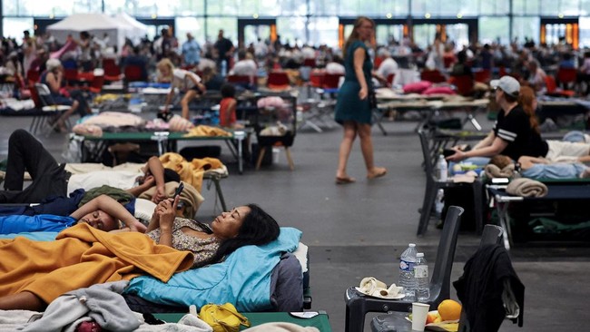 FILE PHOTO: A woman looks at her phone at the Bordeaux-Lac Exhibition Centre, which has been turned into a shelter for people displaced by a wildfire burning nearby amid worsening drought conditions following a heatwave and water shortages across muc