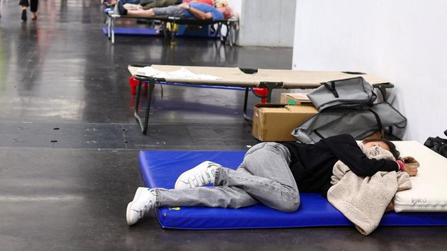 FILE PHOTO: A woman rests at the Bordeaux-Lac Exhibition Centre, which has been turned into a shelter for people displaced by a wildfire burning nearby amid worsening drought conditions following a heatwave and water shortages across much of France,