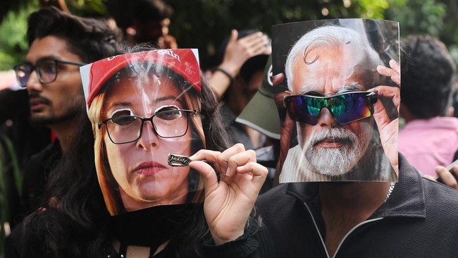 People have images representing India's Prime Minister Narendra Modi and Italy's Prime Minister Giorgia Meloni attached to their faces with glasses, while one of them holds a Melody toffee, as Cockroach Janta Party (CJP) supporters celebrate after th