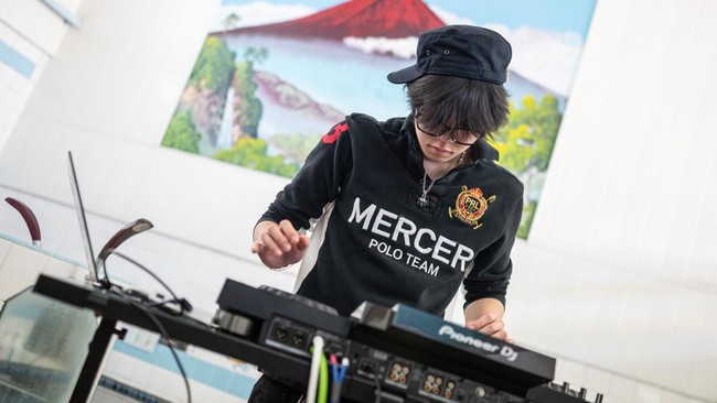 Rihito Mizoguchi, co-founder of the Login.jp project, sets up equipment before a DJ set at the Electric Water Heater sauna in Sumida, Tokyo on April 12, 2026. The collective, Login.jp, moves from shoot to shoot across the archipelago: from a dye work