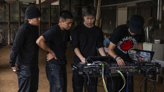 Rihito Mizoguchi (R) and Jun Kim (2nd R), co-founders of the Login.jp project, set up equipment before a DJ set at the Fujiya Somekobo fabric-dyeing workshop in Tokyo on June 24, 2026. The collective, Login.jp, moves from shoot to shoot across the ar