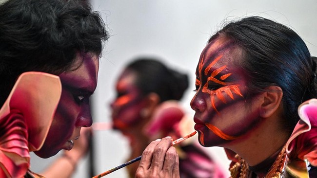 Indonesian performers apply their makeup before taking part in a HEAL (Humanity, Earth, and Life)-themed parade during the Jember Fashion Carnival in Jember, East Java island, on July 26, 2026. (Photo by Juni KRISWANTO / AFP)