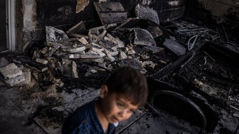 A young Palestinian boy walks in front of a mosque allegedly burned by Israeli settlers in the village of Qusra, south of Nablus in the Israeli-occupied West Bank on July 26, 2026. Palestinian officials said Israeli settlers set fire to two mosques i