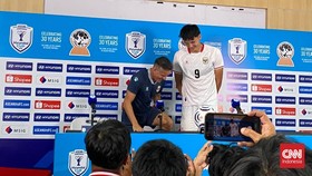 Pelatih Timnas Indonesia John Herdman berkelakar naik kursi untuk mengimbangi tinggi Mitcell Baker dalam sesi foto bersama selepas konferensi pers di Stadion Pakansari, Bogor, Senin (27/7. Indonesia menang 5-1 atas Kamboja di Piala AFF 2026.