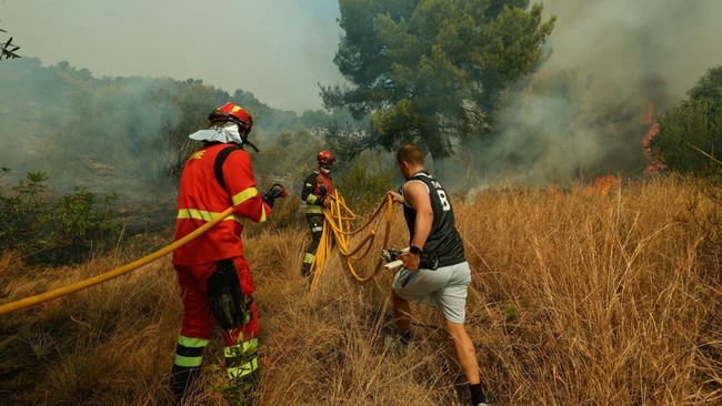 Firefighters work to extinguish flames during a wildfire in Betxi, Spain, July 26, 2026. REUTERS/Eva Manez