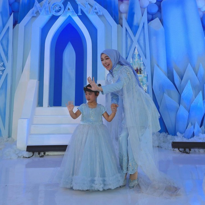 <p>Di acara ini, Moana juga terlihat mengenakan gaun cantik dan manis yang berwarna biru muda. Tema baju yang dikenakannya ini juga sama dengan pakaian yang dipakai sang Bunda. Dalam perayaan ulang tahun Moana, Ricis setelan biru muda dengan aksen payet, yang dipadukan dengan jilbab dan celana berwarna senada. (Foto: Instagram @riaricis1795)</p>
