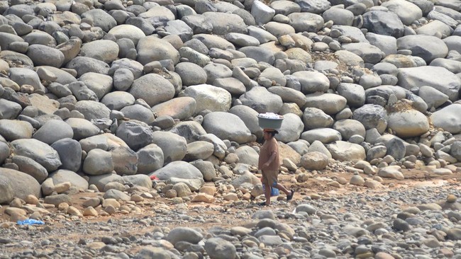 Warga membawa pakaian yang sudah dicuci di tepi sungai Batang Kuranji yang debitnya menyusut di Padang, Sumatera Barat, Selasa (28/7/2026). Sungai Batang Kuranji yang memiliki panjang dari hulu sampai muara sejauh 32,4 kilometer dan rusak oleh banjir