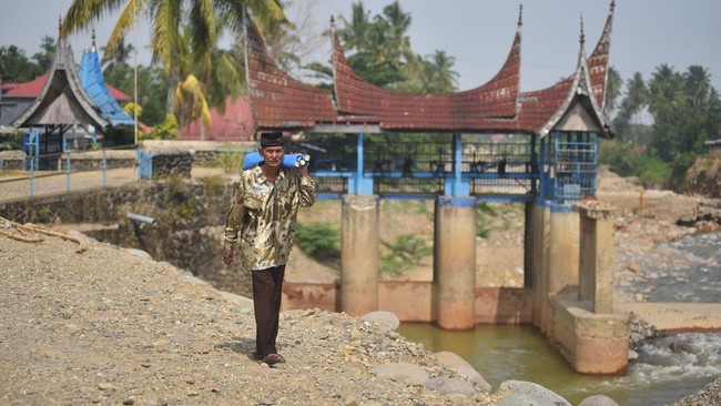 Warga melewati tepi sungai Batang Kuranji yang debitnya menyusut di Padang, Sumatera Barat, Selasa (28/7/2026). Sungai Batang Kuranji yang memiliki panjang dari hulu sampai muara sejauh 32,4 kilometer dan rusak oleh banjir bandang tahun lalu itu kini