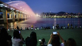 People watch the Moonlight Rainbow Fountain on Banpo Bridge, which stretches over the Han River in Seoul on August 8, 2025. (Photo by Anthony WALLACE / AFP)