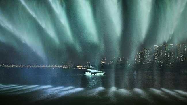 A boat sits beyond the spray from the Moonlight Rainbow Fountain on Banpo Bridge, over the Han River in Seoul on July 28, 2026. (Photo by GREG BAKER / AFP)