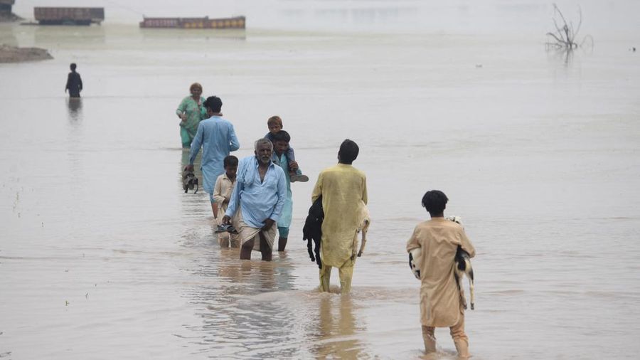 Orang-orang menyeberangi jalan nan tergenang air akibat hujan monsun di Muridke, Pakistan, 28 Juli 2026.