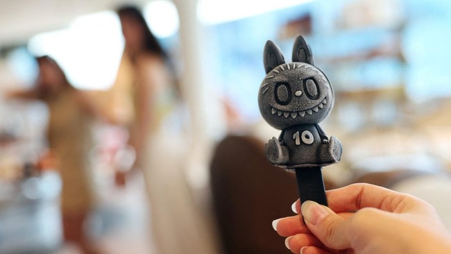 A Pop Mart employee holds up a black sesame Labubu popsicle sold at Pop Mart's first international bakery during their media day at Resorts World Sentosa in Singapore July 29, 2026. REUTERS/Edgar Su