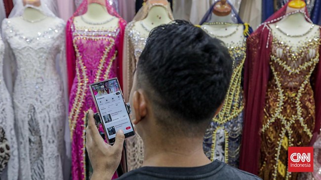 Seorang pedagang mempromosikan dagangannya di salah satu kios Pusat Grosir Tekstil Tanah Abang, Jakarta, Kamis (30/7). (CNN Indonesia/Febria Adha L).