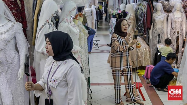 Seorang pedagang mempromosikan dagangannya di salah satu kios Pusat Grosir Tekstil Tanah Abang, Jakarta, Kamis (30/7). (CNN Indonesia/Febria Adha L).