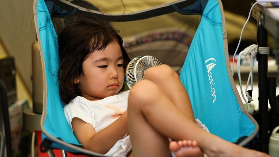 Tsugumi Shimada (3), putri Hirosuke Shimada, menggunakan kipas angin portabel di dalam tenda setelah gempa bumi berkekuatan 7,1 melanda prefektur Kumamoto selatan Jepang, di tengah pemadaman air di wilayah tersebut selama gelombang panas, di Yatsushiro, Jepang, 30 Juli 2026. Khawatir bakal gempa susulan, dia dan personil keluarganya tinggal di tenda di depan rumah mereka.