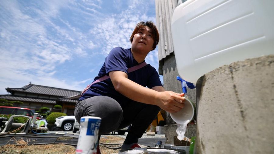 Yuka Shimada (45) mencuci piring di depan rumahnya setelah menerima support air lantaran pemadaman pasokan air di wilayah tersebut setelah gempa bumi berkekuatan 7,1 skala Richter melanda prefektur Kumamoto selatan Jepang, di tengah gelombang panas, di Yatsushiro, Jepang, 30 Juli 2026. Khawatir bakal gempa susulan, dia dan personil keluarganya tinggal di tenda di depan rumah mereka.
