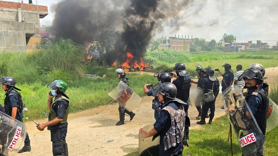 Anggota Kepolisian Nepal berdiri di samping sepeda motor nan terbakar sembari menunggu mobil pemadam kebakaran saat terjadi bentrok antara dua organisasi di Siraha, Nepal, 30 Juli 2026.