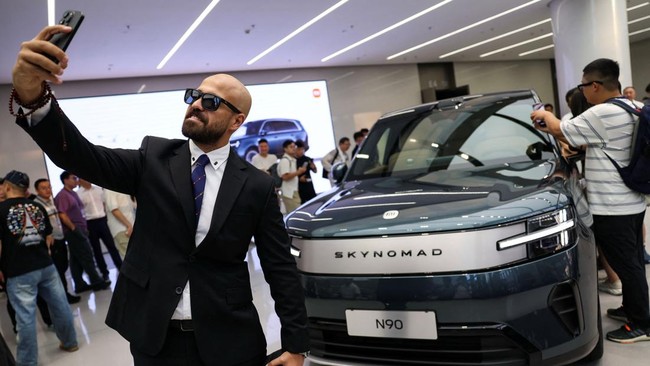 A man takes a selfie near a Xiaomi SkyNomad N90 Max EREV (Extended-Range Electric Vehicle) on display before the car's launch event, in Xiaomi's industrial park, in Beijing, China July 30, 2026. REUTERS/Tingshu Wang