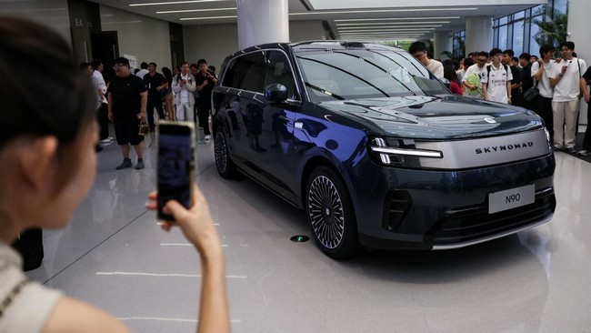 A woman takes photos of a Xiaomi SkyNomad N90 Max EREV (Extended-Range Electric Vehicle) on display before the car's launch event, in Xiaomi's industrial park, in Beijing, China July 30, 2026. REUTERS/Tingshu Wang
