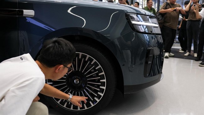 A person checks a tire of a Xiaomi SkyNomad N90 Max EREV (Extended-Range Electric Vehicle) on display before the car's launch event, in Xiaomi's industrial park, in Beijing, China July 30, 2026. REUTERS/Tingshu Wang