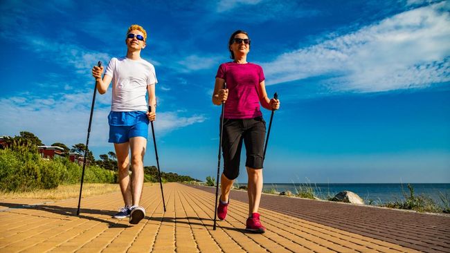 Woman and man nordic walking by sea shore