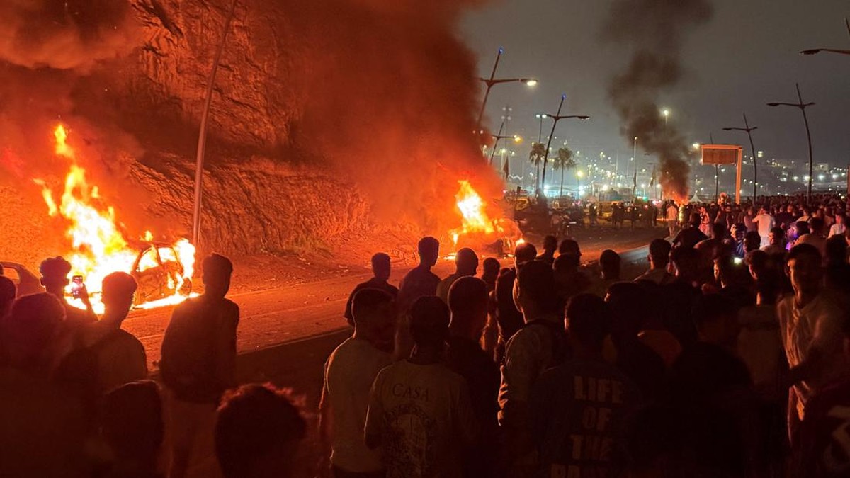 Migrants gather next to burning cars as they wait for a chance to cross to the Spanish enclave of Ceuta, on the Moroccan side of the border in Fnideq, Morocco, July 31, 2026. Picture taken with a mobile phone. REUTERS/Stringer