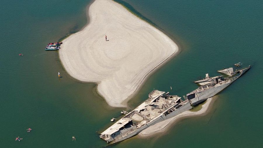 Sebuah tayangan drone menunjukkan orang-orang berenang di dekat kapal perang Jerman yang tenggelam dari Perang Dunia II, yang terlihat karena rendahnya permukaan Sungai Danube akibat kekeringan dan panas ekstrem, di Prahovo, Serbia, 30 Juli 2026.