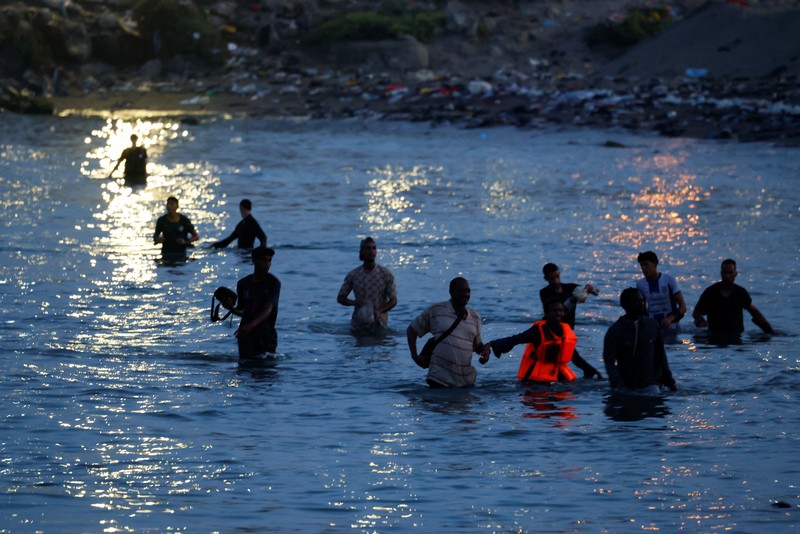 Migrants walk on the Moroccan side of the border, after mass crossings of migrants on foot and by sea from Morocco into Spanish territory, as seen from Cueta, Spain, August 1, 2026. REUTERS/Jon Nazca
