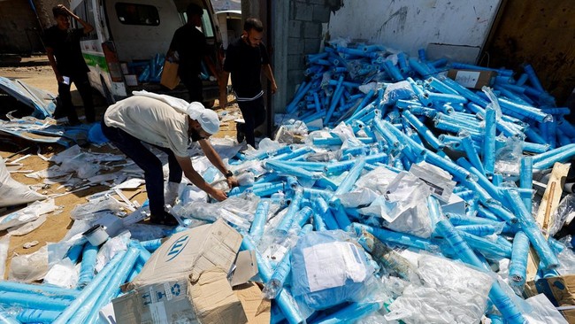 A Palestinian man sorts water filtration cartridges, while recovering medical supplies which were stored in a medicine warehouse,after it was hit in an overnight Israeli strike according to medics, in Deir al-Balah, in the central Gaza Strip, August