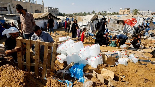 Palestinians inspect the site of an overnight Israeli strike on a medicine warehouse, according to medics, next to tents sheltering displaced Palestinians, in Deir al-Balah, in the central Gaza Strip, August 1, 2026, displaced Palestinians sheltering