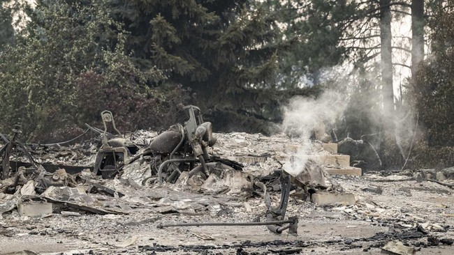 A burned motorcycle sits in the ashes of burned out residential home in the Balboa neighborhood of Spokane, Washington, on August 2, 2026. Fast-moving fires left a trail of destruction in the northwestern US city of Spokane on Sunday, with officials
